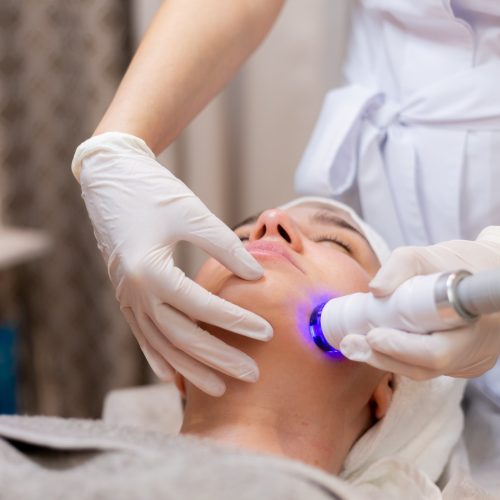 mloda-piekna-dziewczyna-lezy-na-stole-kosmetyczki-i-otrzymuje-zabiegi-profesjonalnym-aparatem-do-odmladzania-i-nawilzania-skory